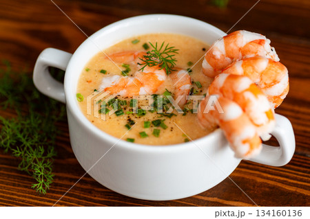 Hot savory shrimp soup with dill and chives on wooden table 134160136