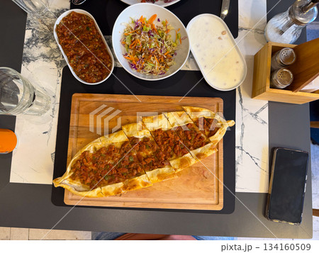 Fresh pide sliced on wooden board. Lunch meal, comfort food, Turkish cuisine tradition, dining moment and homemade baked serving. Fresh pide sliced on wooden board. Lunch meal, comfort food, Turkish cuisine tradition, dining moment and homemade baked serving. 134160509