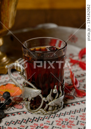 Close-up of a glass of hot tea with berries in a metal cup holder Close-up of a glass of hot tea with berries in a metal cup holder 134162062