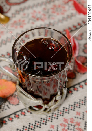 Close-up of a glass of hot tea with berries in a metal cup holder 134162063