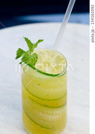 Close-up of a glass of summer drink with cucumber, mint and a straw. 134162092
