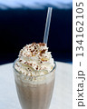 Chocolate milkshake with whipped cream and cocoa chips in a tall glass. 134162105