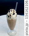 Chocolate milkshake with whipped cream and cocoa chips in a tall glass. 134162106