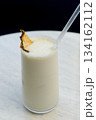 Vanilla milkshake with ice garnished with dried pineapple and a straw 134162112