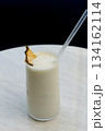 Vanilla milkshake with ice garnished with dried pineapple and a straw 134162114