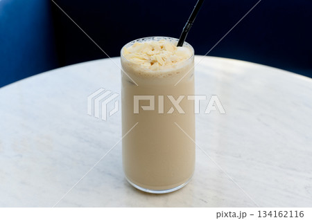 Tall glass of iced latte with almond flakes 134162116