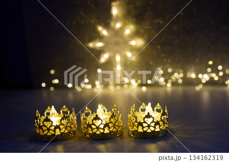 Candlelit Starry Night. Three ornate candles glow with a star-shaped light backdrop Candlelit Starry Night. Three ornate candles glow with a star-shaped light backdrop 134162319