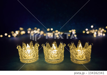 Epiphany. Candlelit Crowns. Three crown-shaped candle holders glowing Epiphany. Candlelit Crowns. Three crown-shaped candle holders glowing 134162341