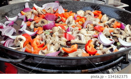 Stirfried vegetables at bustling market, Outdoor market stall serving sizzling vegetable medley, Crowd gathers around as vendor cooks flavorful stirfried vegetables at festive outdoor market 134162375