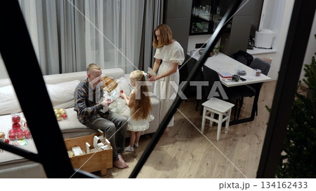 Joyful family unwrapping vintage christmas ornaments, sitting together on comfortable sofa in bright, contemporary living space, sharing holiday memories Joyful family unwrapping vintage christmas ornaments, sitting together on comfortable sofa in bright, contemporary living space, sharing holiday memories 134162433