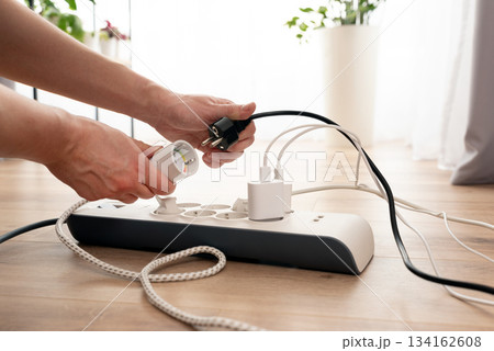 Person is plugging in a device to a power strip Person is plugging in a device to a power strip 134162608