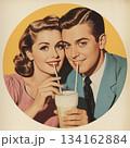 A man and woman enjoy one milkshake through two straws, classic 1950s vibe 134162884
