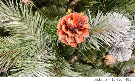 Close-up of a decorative pinecone on the frosted branch of an artificial Christmas tree a detailed holiday texture Close-up of a decorative pinecone on the frosted branch of an artificial Christmas tree a detailed holiday texture 134164495