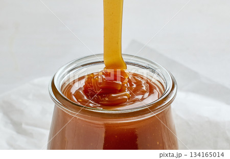 freshly cooked homemade caramel sauce pouring in jar 134165014