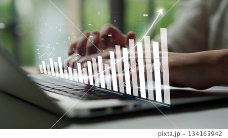 Digital financial growth concept with hands typing on laptop and ascending bar chart overlay representing success in business and technology innovation Copula Digital financial growth concept with hands typing on laptop and ascending bar chart overlay representing success in business and technology innovation Copula 134165942