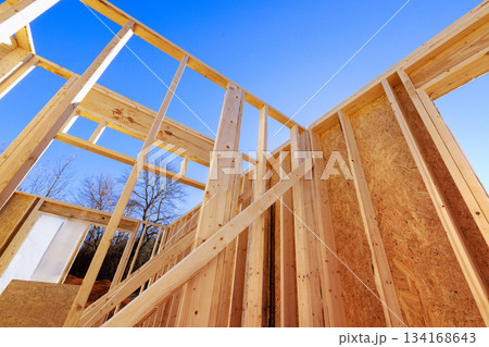 Sunlight shines on wooden framing beams of house under construction in quiet location 134168643