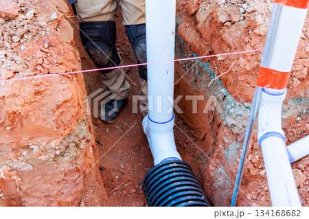 Workers install drainage system in trench at construction site 134168682