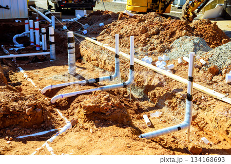 Construction site shows newly installed plumbing pipes in dirt area for building progress Construction site shows newly installed plumbing pipes in dirt area for building progress 134168693