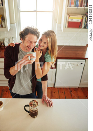 Hugging, coffee or happy couple laughing in kitchen at home bonding or enjoying quality time together. Embrace, affection or above of funny mature man relaxing or drinking tea with woman at home 134168811