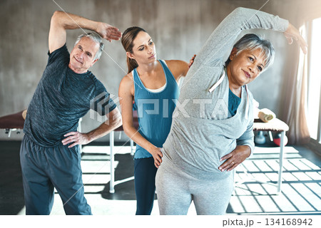 Stretching, helping and senior people with personal trainer in class for fitness, wellness or rehabilitation. Health coach, workout or retirement with elderly patient, man or female in gym warm up 134168942