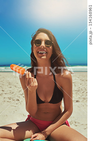 Ice cream, beach smile and woman portrait on holiday by the sea and blue sky with happiness. Sun, sand and young female person face with a happy travel and lens flare by ocean in summer on vacation Ice cream, beach smile and woman portrait on holiday by the sea and blue sky with happiness. Sun, sand and young female person face with a happy travel and lens flare by ocean in summer on vacation 134168961