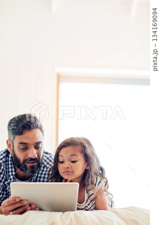Love, digital tablet and father with daughter on a bed for reading, story and learning in their home together. Family, streaming and parent and girl relax in bedroom online with ebook or subscription Love, digital tablet and father with daughter on a bed for reading, story and learning in their home together. Family, streaming and parent and girl relax in bedroom online with ebook or subscription 134169094