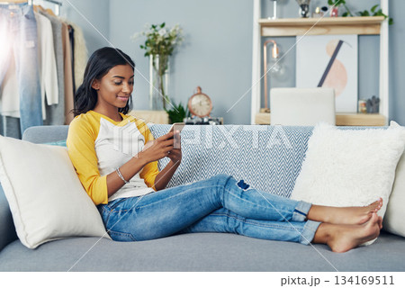 Sofa, phone and relax woman scroll, typing or message social network user, gen z contact or person. Lounge couch, home apartment and Indian girl reading cellphone, online shopping or app website info 134169511
