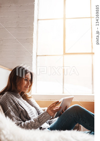 Window, tablet and credit card with a woman online shopping on a sofa in the living room of her home. Ecommerce, finance and fintech banking with a young female user, customer or shopper in a house 134169885