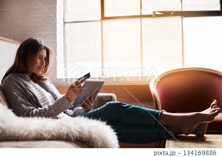 Relax, tablet and credit card with a woman banking online on a sofa in the living room of her home. Ecommerce, financial freedom and shopping with a young female customer or consumer in her house 134169886