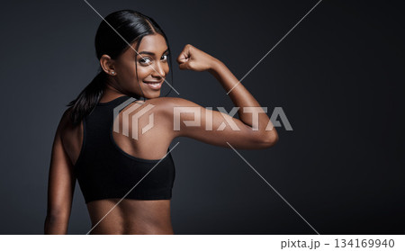 Portrait, smile and woman flexing back in studio isolated on a black background mockup. Strong flex, happy and Indian female athlete with bicep, arm strength or bodybuilder muscle, fitness or workout Portrait, smile and woman flexing back in studio isolated on a black background mockup. Strong flex, happy and Indian female athlete with bicep, arm strength or bodybuilder muscle, fitness or workout 134169940