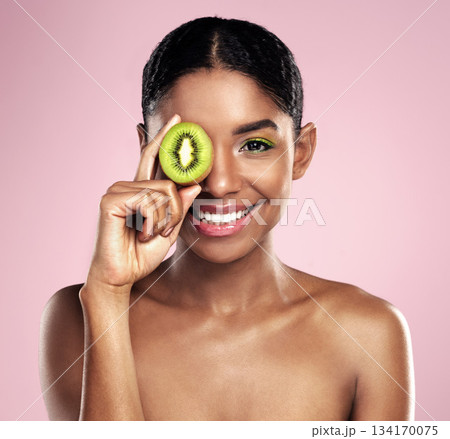 Portrait, woman and kiwi for beauty in studio, pink background and healthy vitamin c cosmetics. Face of happy african model, green fruits and nutrition of natural skincare, organic benefits and glow Portrait, woman and kiwi for beauty in studio, pink background and healthy vitamin c cosmetics. Face of happy african model, green fruits and nutrition of natural skincare, organic benefits and glow 134170075
