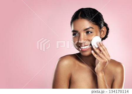 Skincare, mockup and happy woman with cotton pad on face, smile and makeup removal with skin product in studio. Dermatology, facial cleansing cosmetics and African model isolated on pink background. Skincare, mockup and happy woman with cotton pad on face, smile and makeup removal with skin product in studio. Dermatology, facial cleansing cosmetics and African model isolated on pink background. 134170114