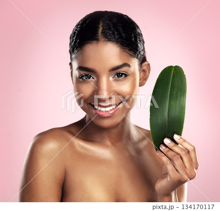 Portrait, happy woman and leaves for natural beauty in studio, pink background and eco friendly vegan cosmetics. Face, african model and healthy skincare of plants, green leaf and sustainable shine 134170117