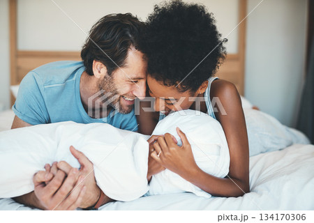 Happy interracial couple, bed and laughing in relax for intimate morning, bonding or relationship at home. Man and woman smiling with laugh in joyful happiness or relaxing weekend together in bedroom 134170306