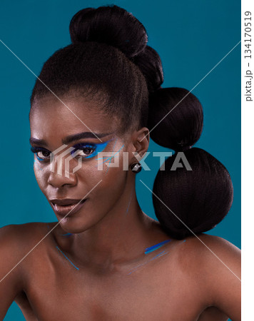 Portrait, makeup and bold with a model black woman in studio on a blue background for hair or cosmetics. Face, confidence and fashion with an attractive young female person posing to promote beauty Portrait, makeup and bold with a model black woman in studio on a blue background for hair or cosmetics. Face, confidence and fashion with an attractive young female person posing to promote beauty 134170519