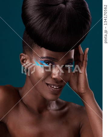 Portrait, makeup and happy with an african woman in studio on a blue background for hair or cosmetics. Eyeshadow, smile and fashion with an attractive young female model at the salon for style Portrait, makeup and happy with an african woman in studio on a blue background for hair or cosmetics. Eyeshadow, smile and fashion with an attractive young female model at the salon for style 134170562