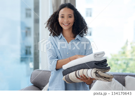 Portrait, laundry and cleaning with a black woman in her home, holding fresh towels during housework. Smile, fabric and washing with a happy young female cleaner in the living room of her apartment 134170643