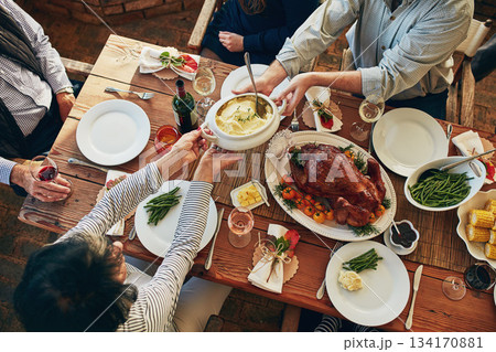 Food, table and family eating together for holiday celebration or dinner party with health vegetables. Above group of people or friends hands sharing lunch meal, chicken or turkey with wine drinks 134170881
