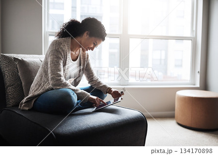 Tablet, credit card and girl on sofa and online shopping in home or ecommerce, paying for retail product and internet store. Latino woman, banking and money for service, digital payment or goods Tablet, credit card and girl on sofa and online shopping in home or ecommerce, paying for retail product and internet store. Latino woman, banking and money for service, digital payment or goods 134170898