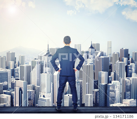 Back, view of the city and a business man standing hands on hips outdoor with a vision or mindset of success. Proud sky and buildings with a male corporate employee looking out over an urban town Back, view of the city and a business man standing hands on hips outdoor with a vision or mindset of success. Proud sky and buildings with a male corporate employee looking out over an urban town 134171186