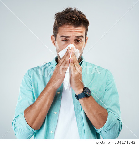 Sick, tissue and portrait of man blowing nose in studio with flu, illness and virus on white background. Health, wellness and face of male person with hayfever, cold symptoms and sneeze for allergy 134171342