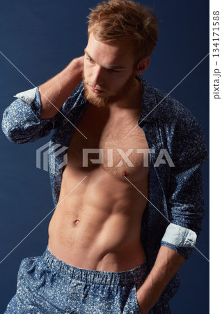Fashion, body and muscle with a man in studio on a blue background wearing an open unbuttoned shirt. Fitness, chest and abs with a handsome young male model posing on a color wall for masculine style Fashion, body and muscle with a man in studio on a blue background wearing an open unbuttoned shirt. Fitness, chest and abs with a handsome young male model posing on a color wall for masculine style 134171588