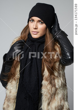 Woman, portrait and fashion in luxury for winter clothing, warmth and fur posing against a gray studio background. Attractive, gorgeous and young female person or model in pose in fashionable clothes 134171589