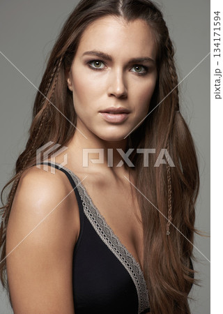Woman, face and portrait in natural beauty of model posing with long hairstyle or makeup against a grey studio background. Isolated young and confident female person with facial cosmetics on backdrop 134171594