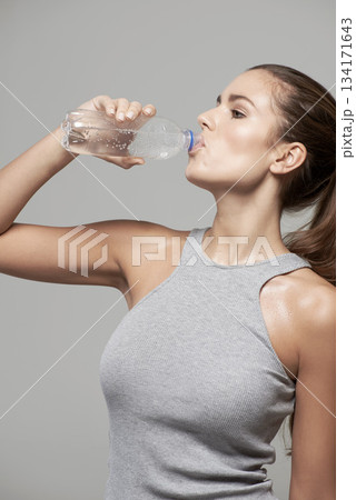 Drinking water, wellness and woman with bottle in studio for healthy body, refreshing and hydration. Diet, fitness and female person on gray background with aqua for wellbeing, detox and thirsty Drinking water, wellness and woman with bottle in studio for healthy body, refreshing and hydration. Diet, fitness and female person on gray background with aqua for wellbeing, detox and thirsty 134171643