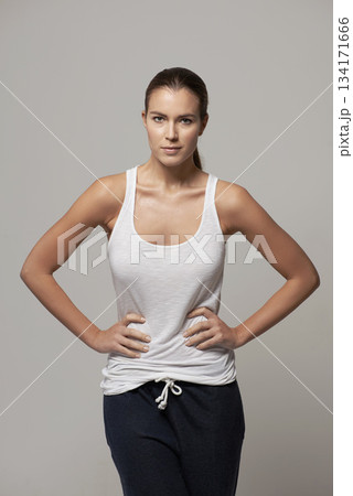 Woman, portrait and hands on hip in confidence for body fitness, health and wellness against a gray studio background. Proud or confident female person or model posing in pride for exercise clothing Woman, portrait and hands on hip in confidence for body fitness, health and wellness against a gray studio background. Proud or confident female person or model posing in pride for exercise clothing 134171666