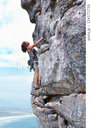 Rock climbing, blue sky and challenge with woman on mountain for adventure, travel and explore. Strong, freedom and cliff with female climber training in nature for courage, safety and workout 134171738