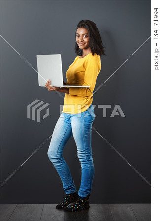 Portrait, happy indian woman standing with laptop and in wall background. Social media or networking, technology or communication and smiling African female worker with mockup in studio backdrop. Portrait, happy indian woman standing with laptop and in wall background. Social media or networking, technology or communication and smiling African female worker with mockup in studio backdrop. 134171994