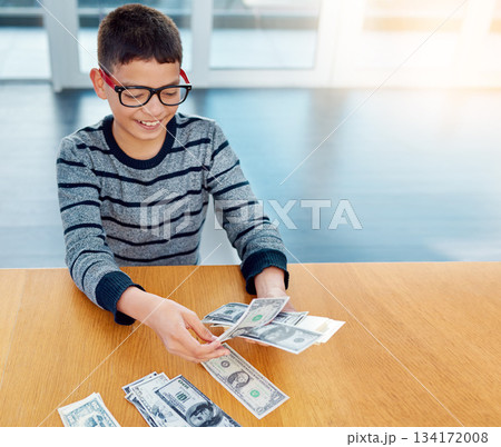 Savings, young child counting money and sitting at desk at his home. Finance or investing, financial management or wealth planning and happy male kid with cash for future investment in house Savings, young child counting money and sitting at desk at his home. Finance or investing, financial management or wealth planning and happy male kid with cash for future investment in house 134172008