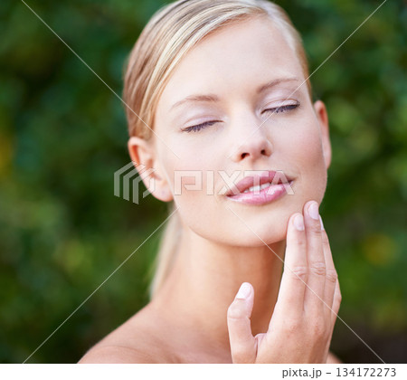 Skincare, beauty and a woman touching face in a garden nature or backyard. Content, wellness and a young lady feeling skin for moisturizing, satisfaction or wellbeing glow from a spa treatment Skincare, beauty and a woman touching face in a garden nature or backyard. Content, wellness and a young lady feeling skin for moisturizing, satisfaction or wellbeing glow from a spa treatment 134172273